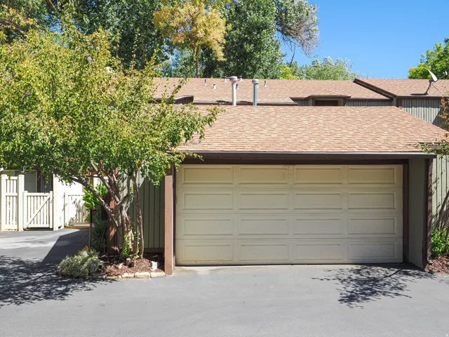 Attached single-car garage with a panel-style door, asphalt driveway, and a shingle roof