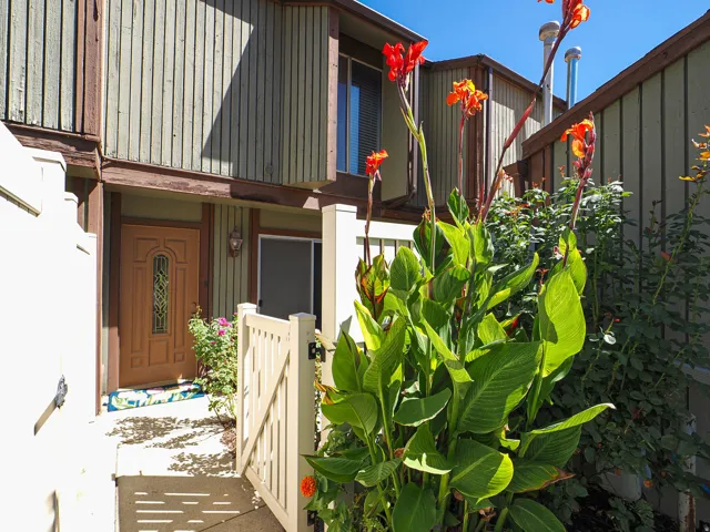 Gated entry with a decorative wood door, wall-mounted exterior light fixture, and vertical siding