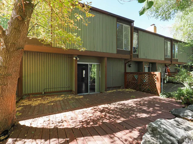 Expansive wood-finish deck with a sliding glass door entry, vertical siding exterior, and integrated lattice privacy screening