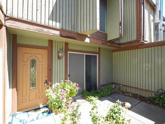 Entryway featuring a decorative paneled door with leaded glass, an exterior wall sconce, and board-and-batten siding