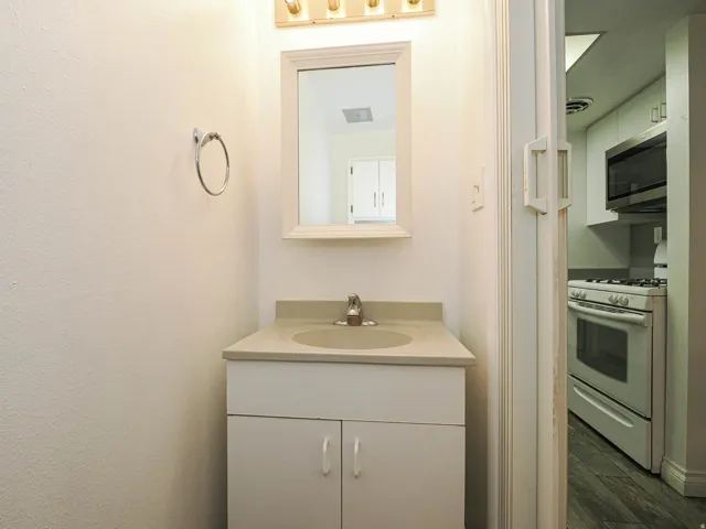 White vanity with integrated sink, light-toned countertop, and framed mirror