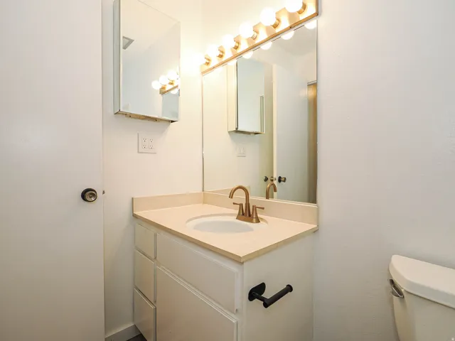 Vanity with an integrated sink, bronze-finish faucet, and a wall-mounted medicine cabinet
