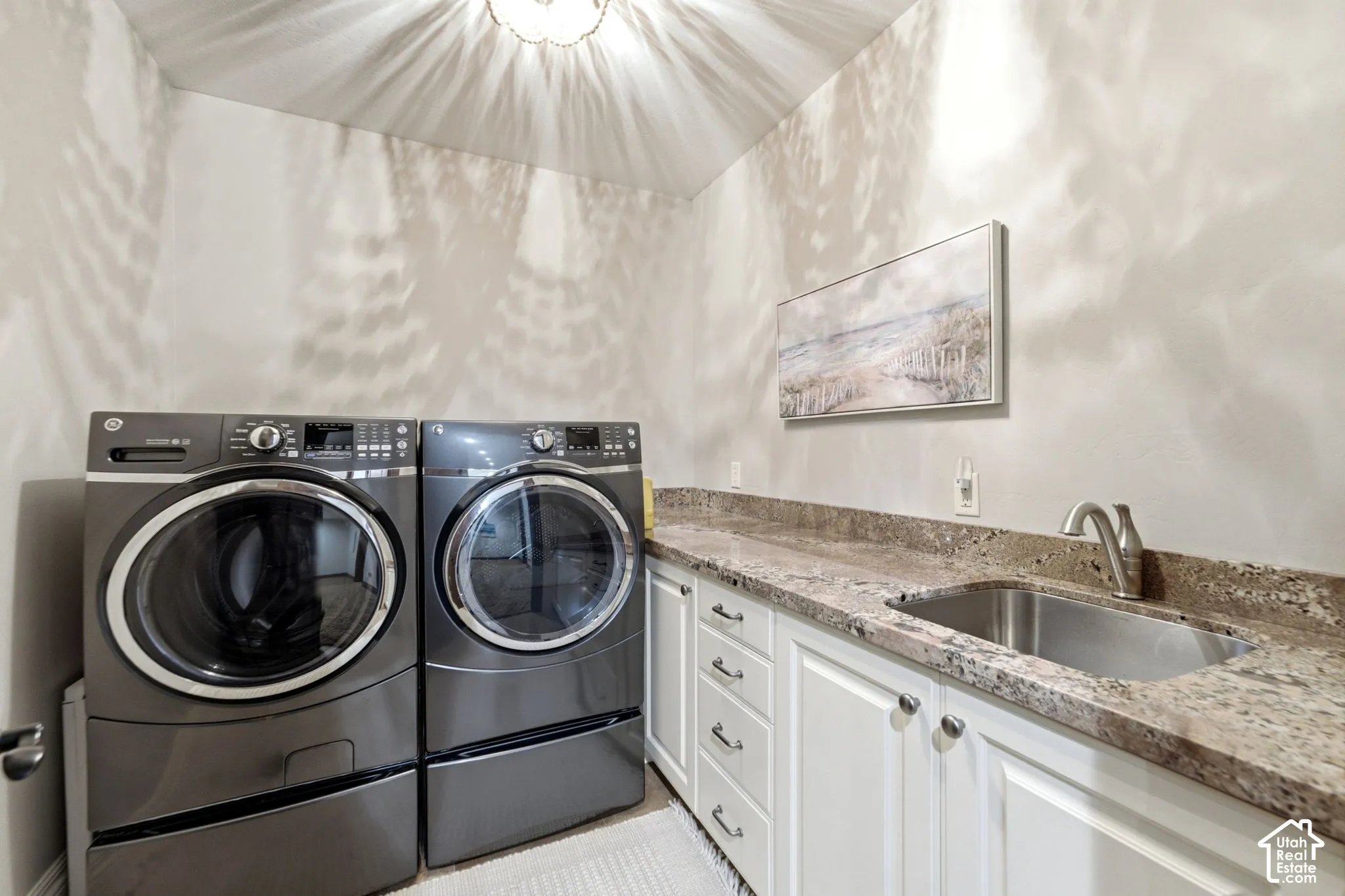 Built-in cabinetry with white shaker-style doors, stone-finish countertop, and undermount stainless steel sink with a gooseneck faucet