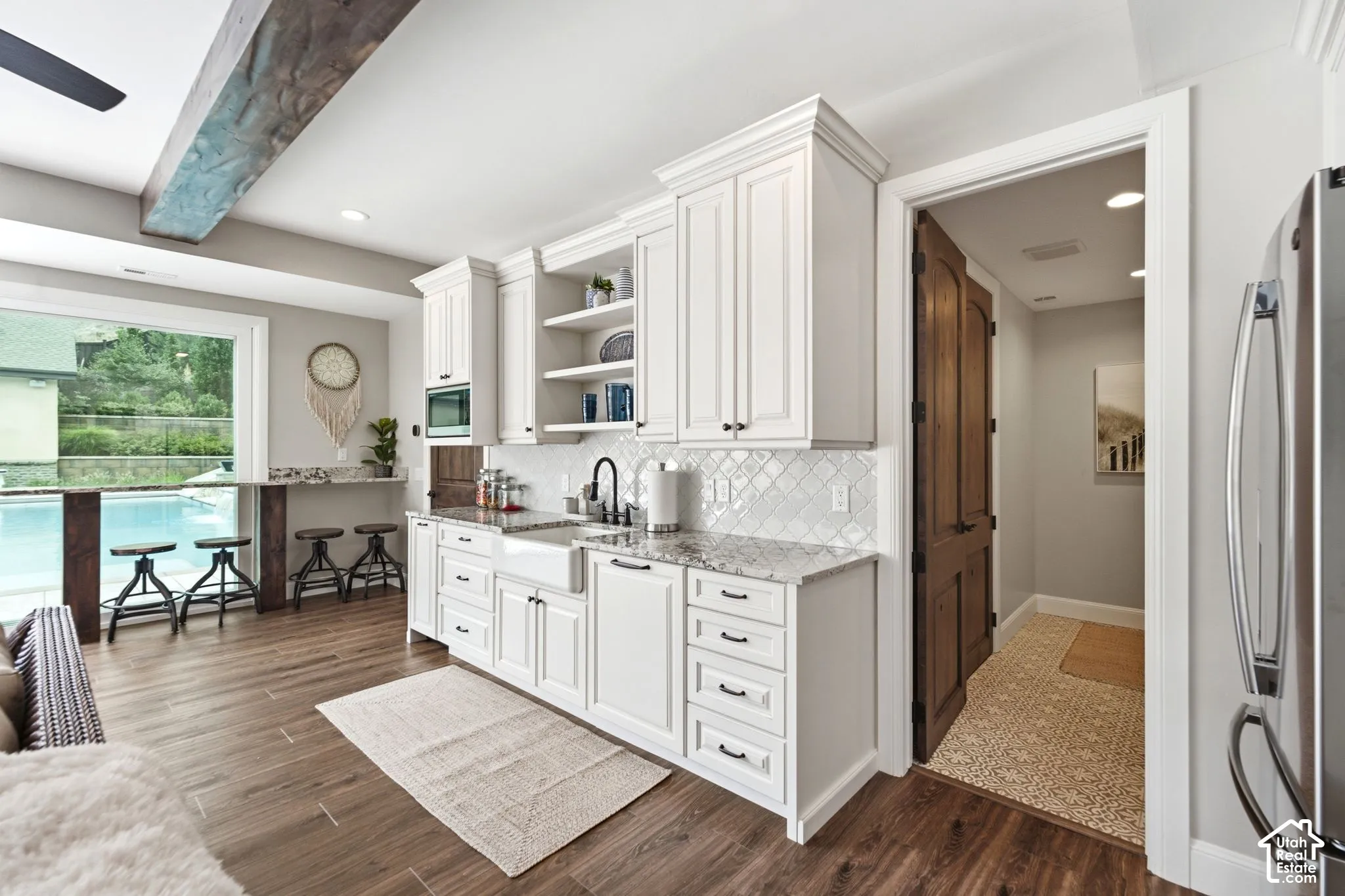 Casita -White shaker-style cabinetry with crown molding, granite countertops, a white apron-front sink, and a diamond-patterned tile backsplash