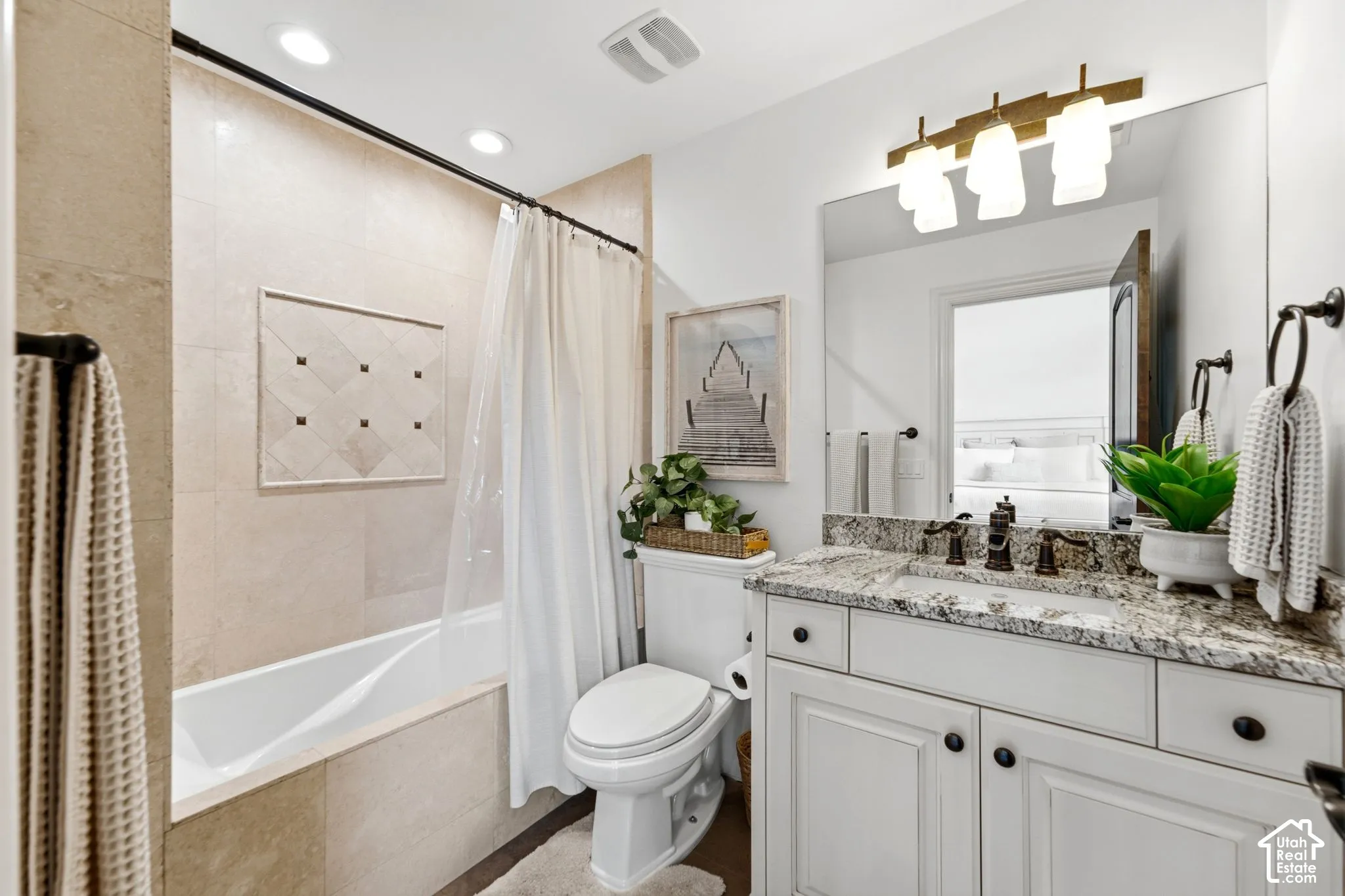 White vanity with dark hardware, stone countertop, integrated sink, and bronze-finish light fixture
