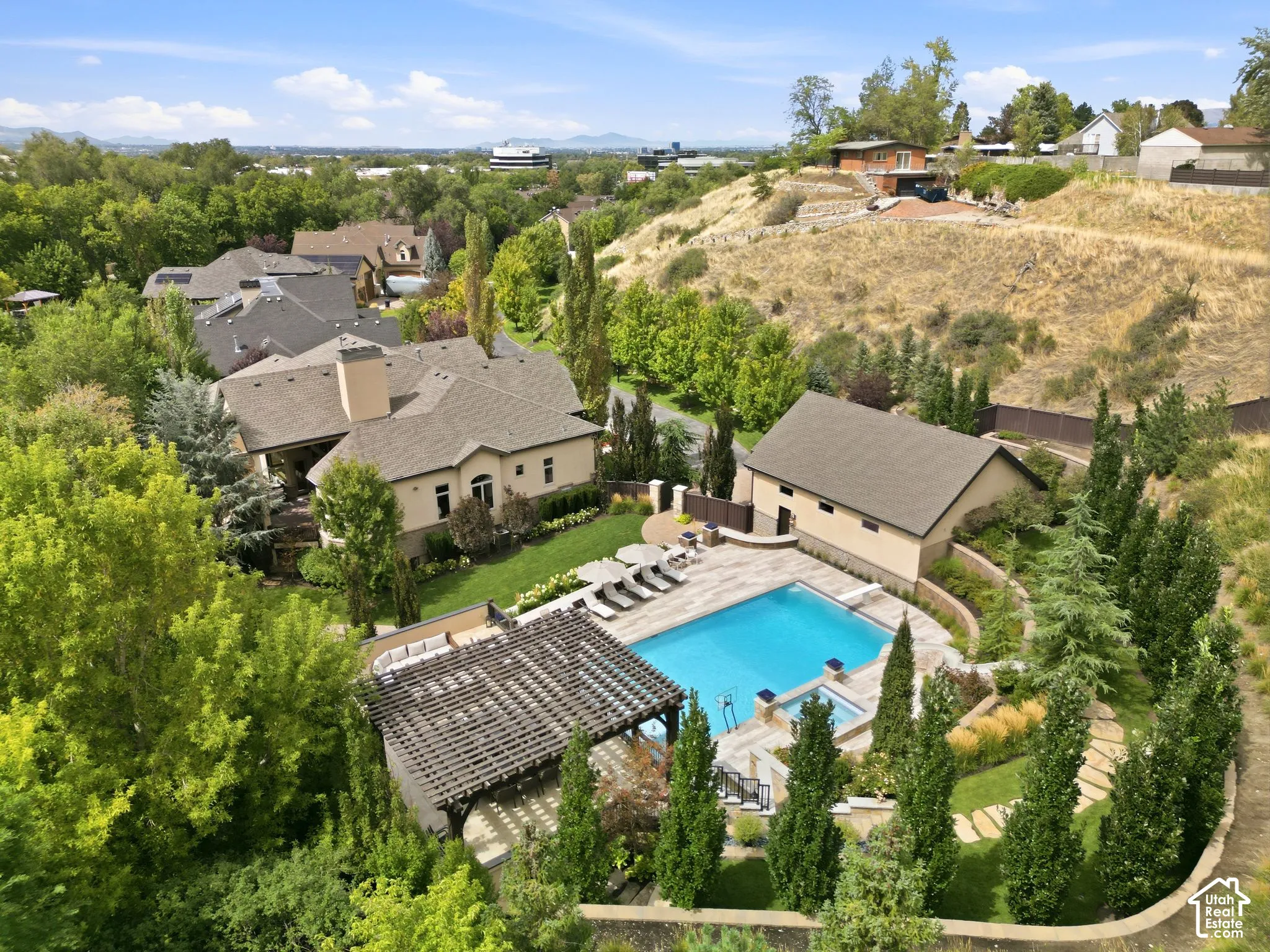 Expansive property featuring a large swimming pool, integrated spa, adjacent pool house, and a pergola-covered patio area