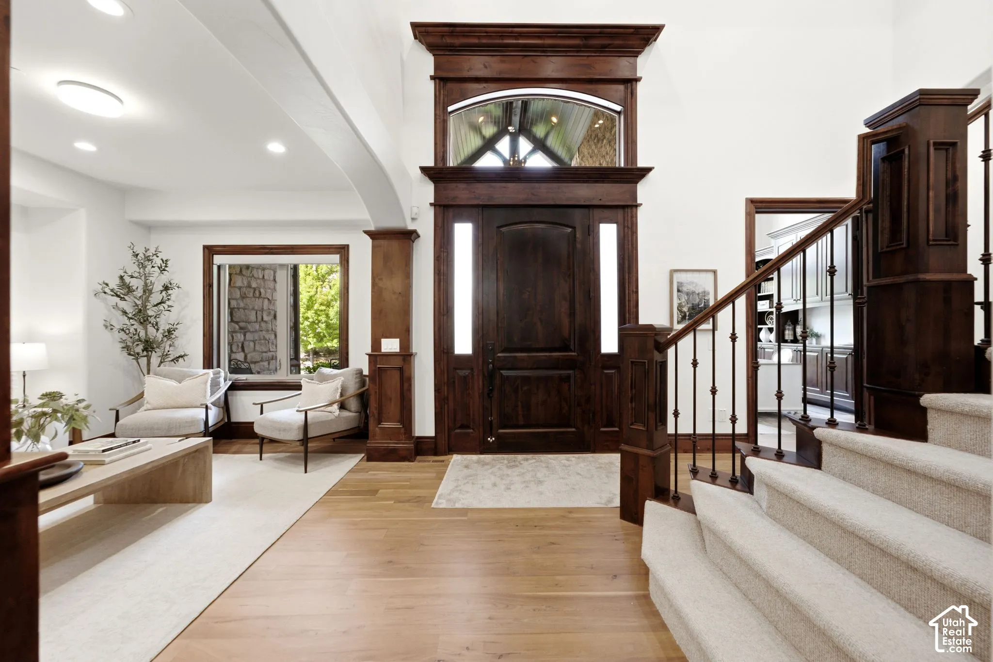 Grand entryway featuring a dark wood door with sidelights, a large arched transom window, and light wood-finish flooring