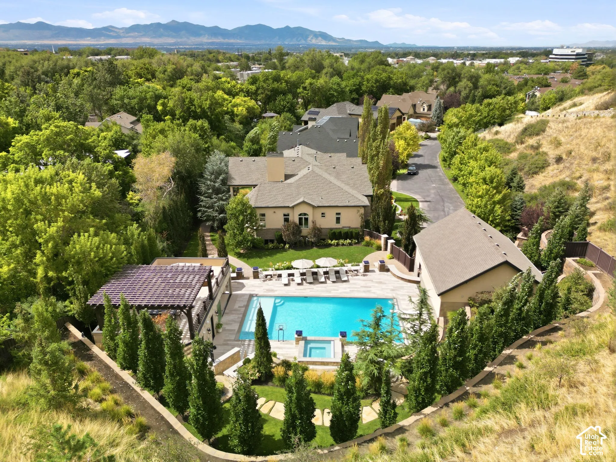 Expansive outdoor living area featuring a large swimming pool, integrated spa, and an adjacent pergola-covered patio