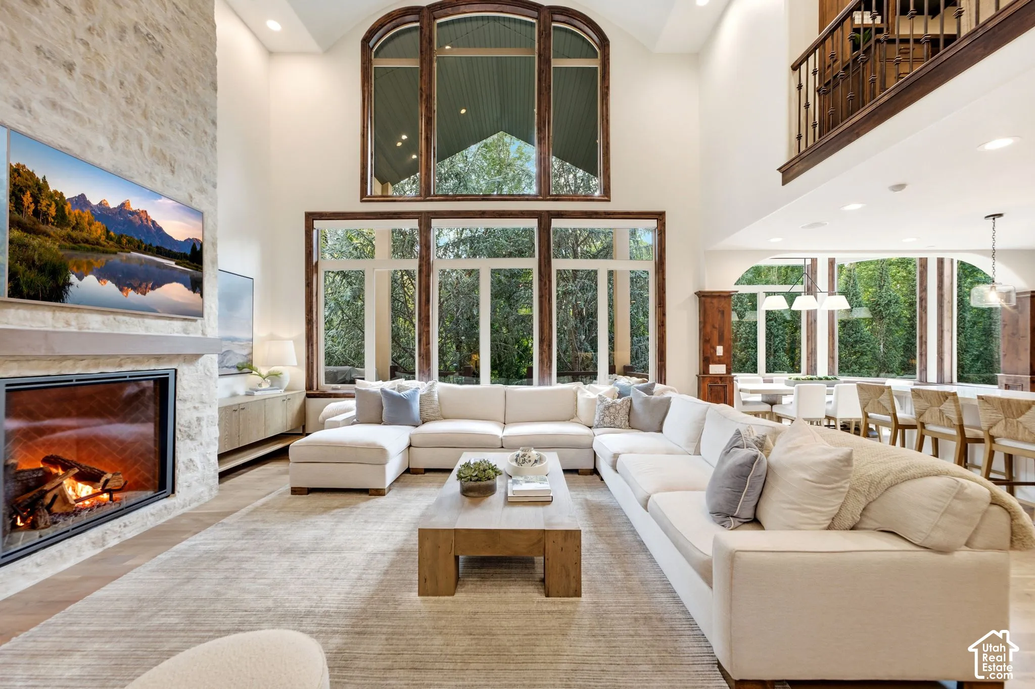 Two-story living area with a stone fireplace, wood-finish flooring, and a second-story interior balcony with wood railing