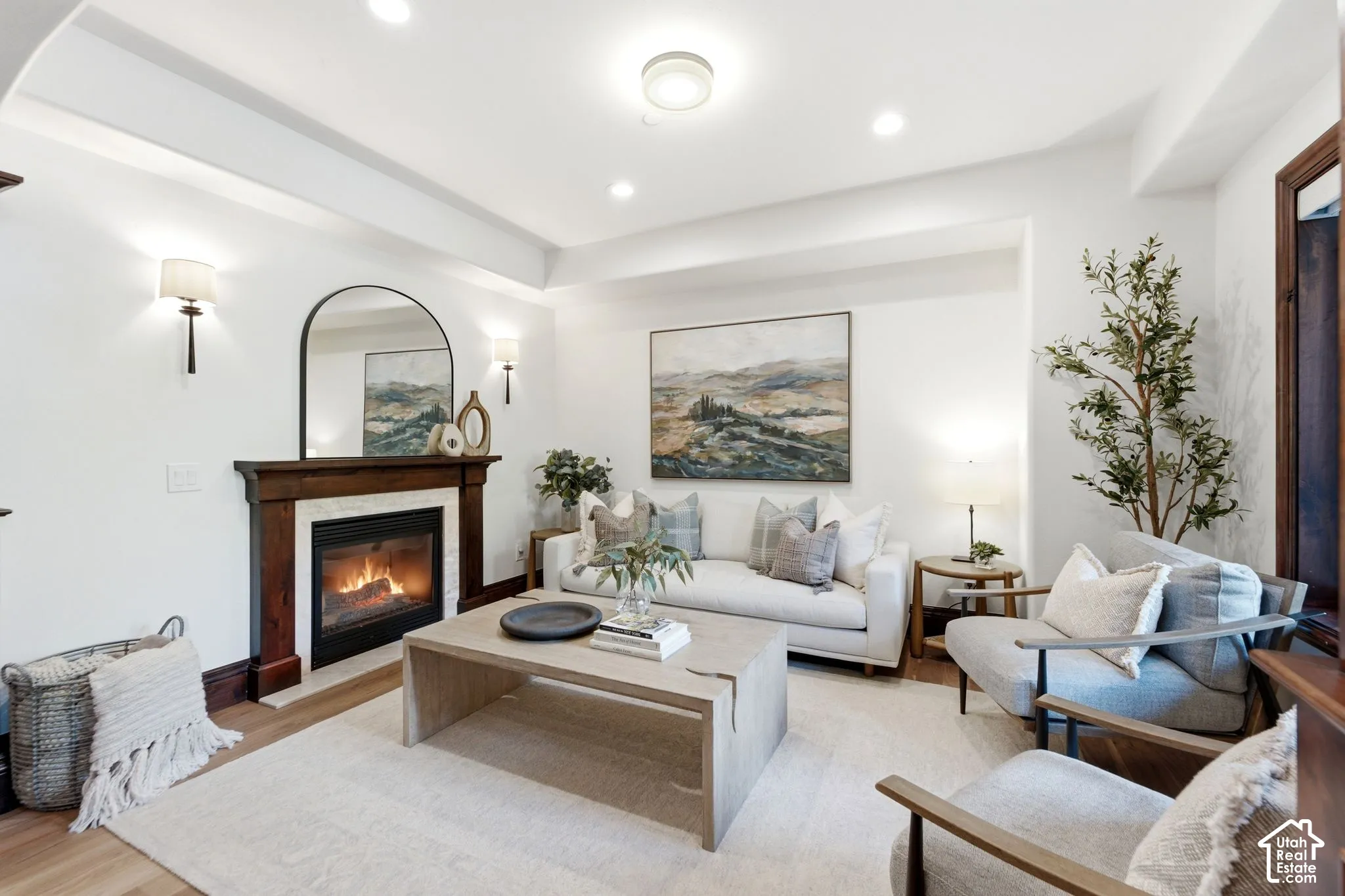 Recessed lighting, wood-finish flooring, fireplace with a wood mantle, decorative wall sconces, and a tray ceiling