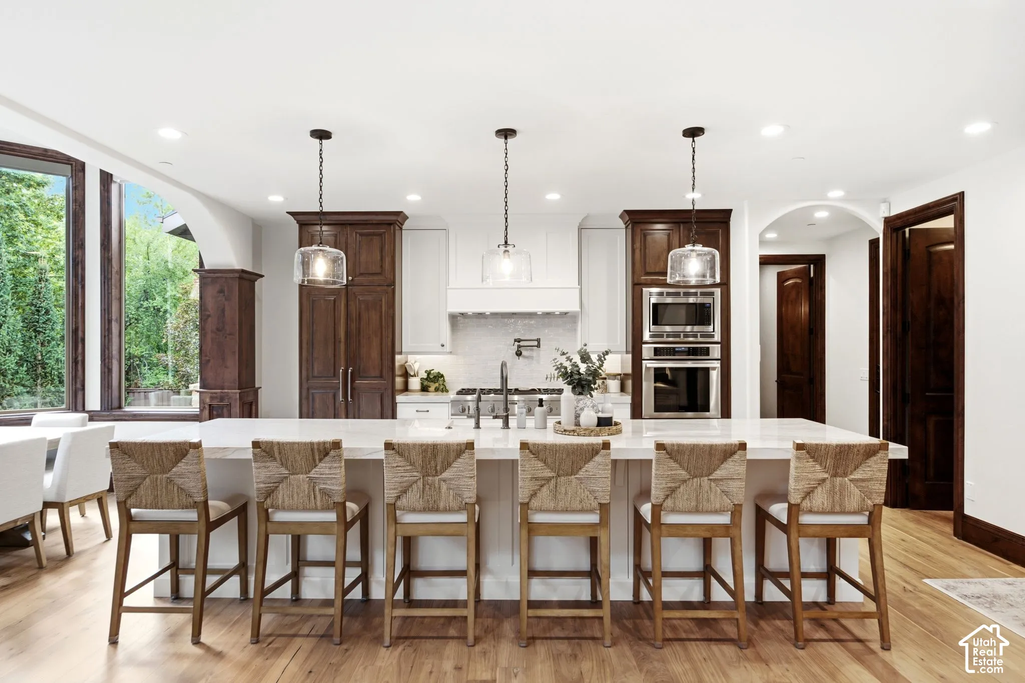 Kitchen featuring a large central island, recessed lighting, wood-finish flooring, stainless steel built-in appliances, and a tiled backsplash