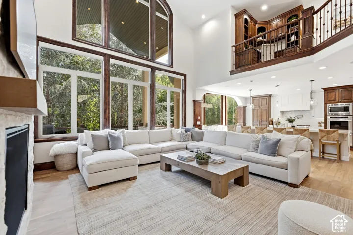 Two-story living area with expansive windows, stone-clad fireplace, and a built-in upper-level library
