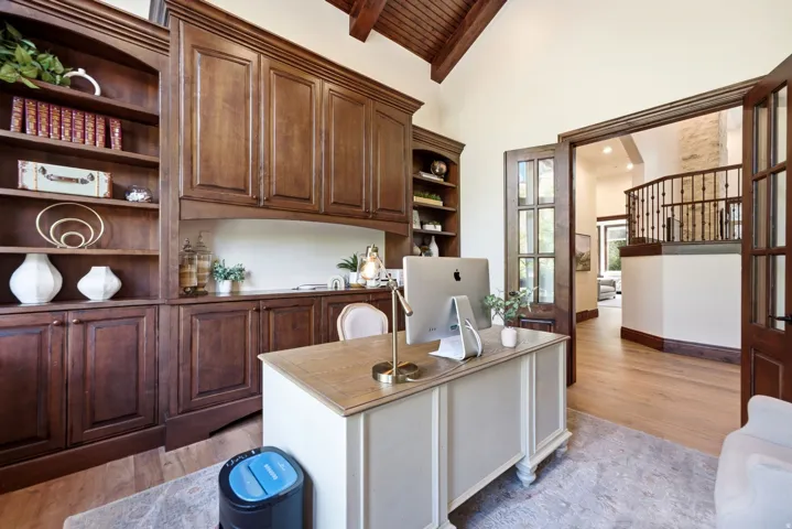 Built-in cabinetry with integrated shelving, vaulted wood-beam ceiling, and wood-finish flooring