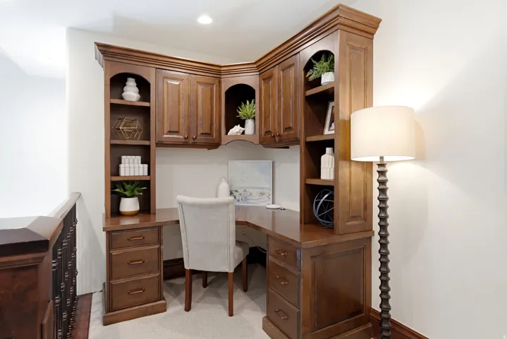 Built-in corner desk featuring rich wood cabinetry, integrated shelving, and drawer storage