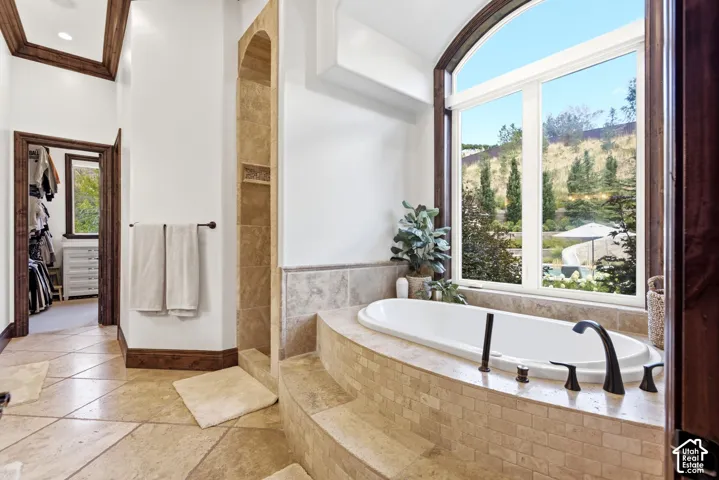 Deep soaking tub with dark bronze fixtures, set against an arched picture window
