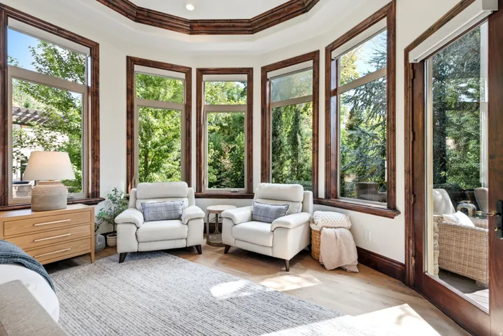 Bay window design with rich wood trim and crown molding, wood-finish flooring, and a glass-paneled exterior door