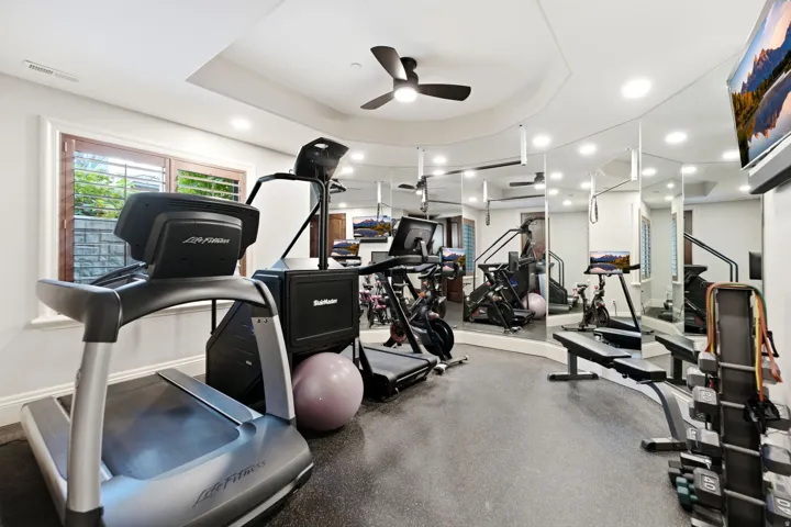 Recessed lighting, ceiling fan, mirrored wall, full-wall window, and tray ceiling