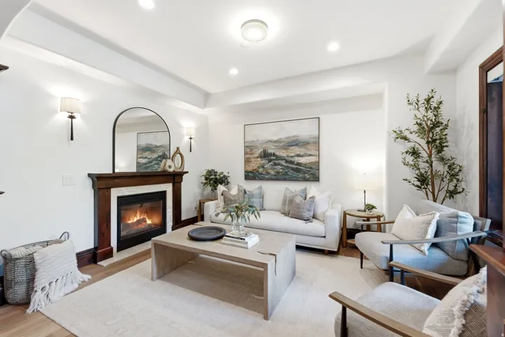 Recessed lighting, wood-finish flooring, fireplace with a wood mantle, decorative wall sconces, and a tray ceiling