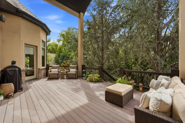 Expansive outdoor deck featuring composite decking, dark wood railings, and a stucco exterior with stone accents