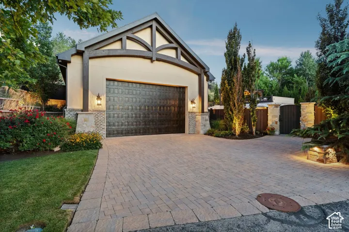 Detached Garage -Paved driveway with stone accents, wrought iron-style garage door, stucco exterior, and decorative exterior lighting