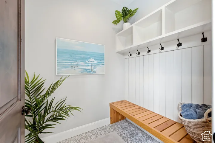 Casita Dressing AreaBuilt-in storage cubbies, white shiplap wall paneling, integrated coat hooks, natural wood-finish bench, and patterned floor tile