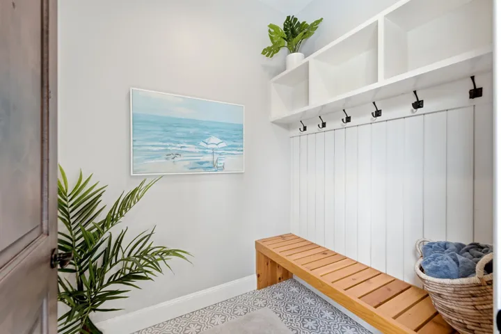 Casita Dressing AreaBuilt-in storage cubbies, white shiplap wall paneling, integrated coat hooks, natural wood-finish bench, and patterned floor tile