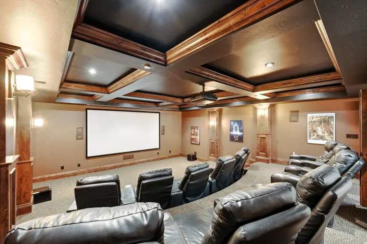 Home theater with a large projection screen, recessed lighting, and wood-paneled accents