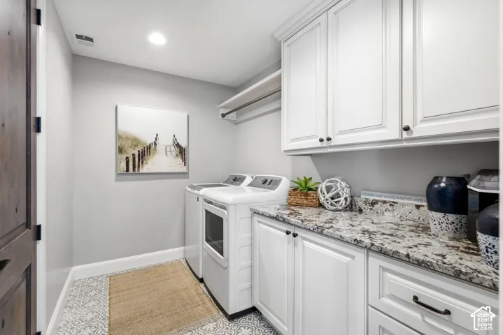 Laundry area with white cabinetry, granite-style countertop, and patterned floor tile