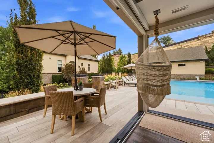Expansive patio with light-toned tile flooring, direct pool access, and a built-in stone planter