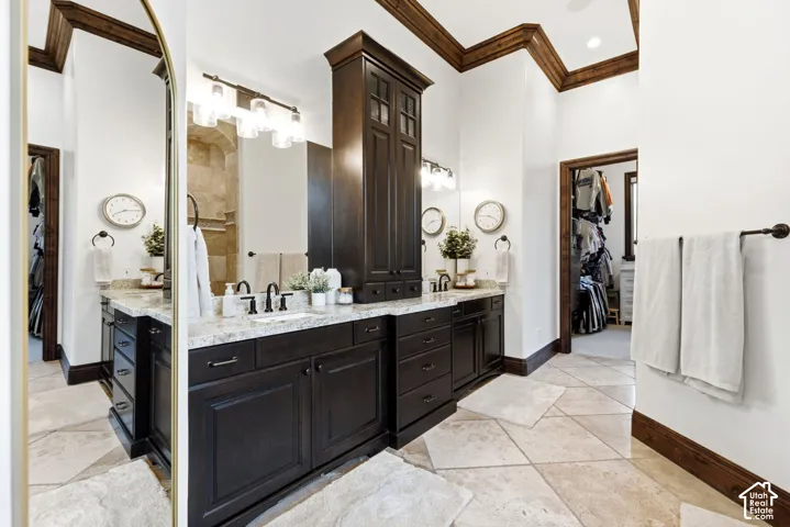 Dual vanity with stone countertops and undermount sinks, dark wood-finish cabinetry, and decorative crown molding