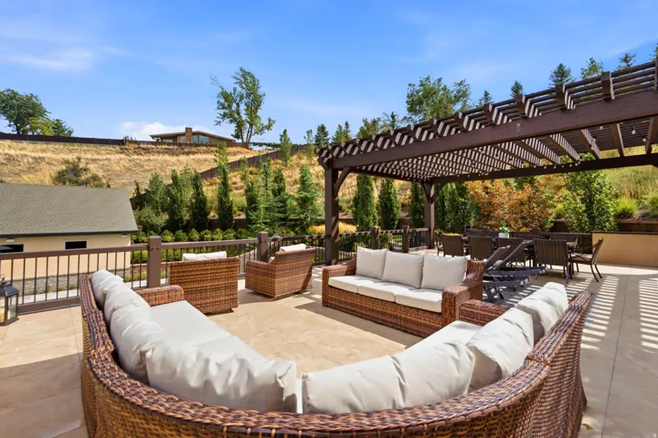 Expansive outdoor patio featuring a large pergola, tile flooring, and a decorative railing
