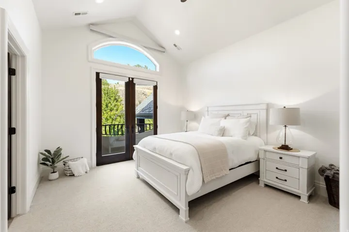 Vaulted ceiling with recessed lighting, arched transom window, double French doors, and light-toned carpeting