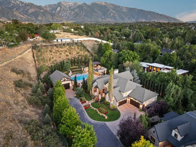 Expansive property featuring a multi-level residence, swimming pool, extensive hardscaping, mature landscaping, and an integrated garage