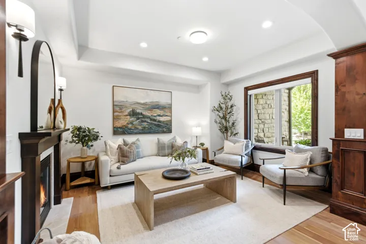 Living area featuring rich wood-finish flooring, a built-in fireplace with a mantel, recessed lighting, and a window with wood trim