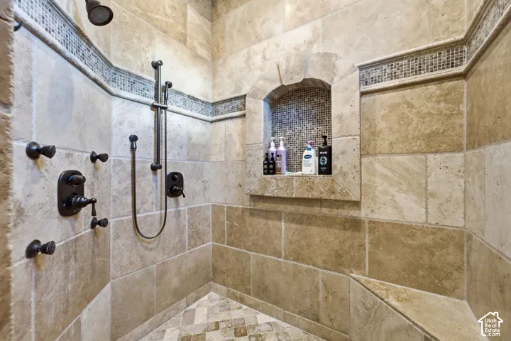 Stone-tiled shower featuring a recessed niche, an integrated bench, and a mosaic tile accent band