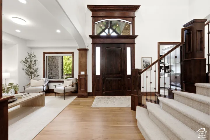 Grand entryway featuring a dark wood door with sidelights, a large arched transom window, and light wood-finish flooring
