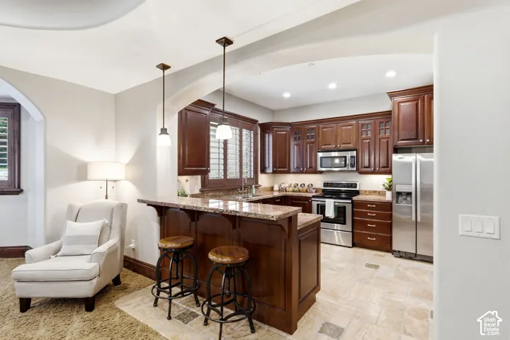 Kitchen featuring wood cabinetry, stainless steel appliances, and stone countertops