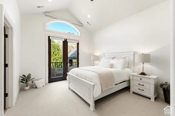 Vaulted ceiling with recessed lighting, arched transom window, double French doors, and light-toned carpeting
