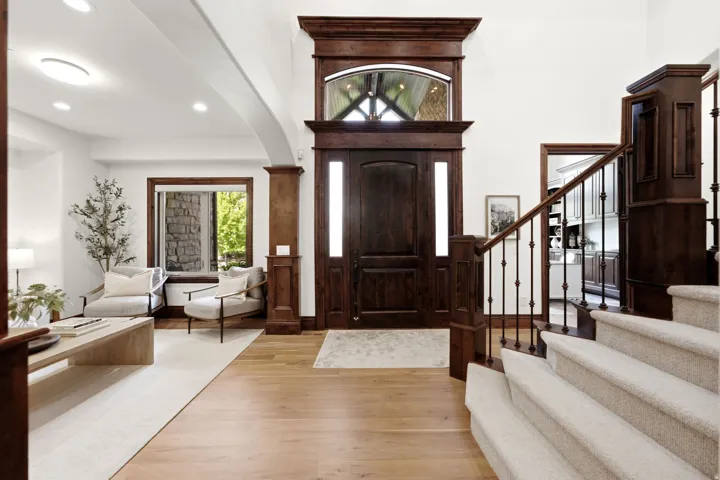 Grand entryway featuring a dark wood door with sidelights, a large arched transom window, and light wood-finish flooring