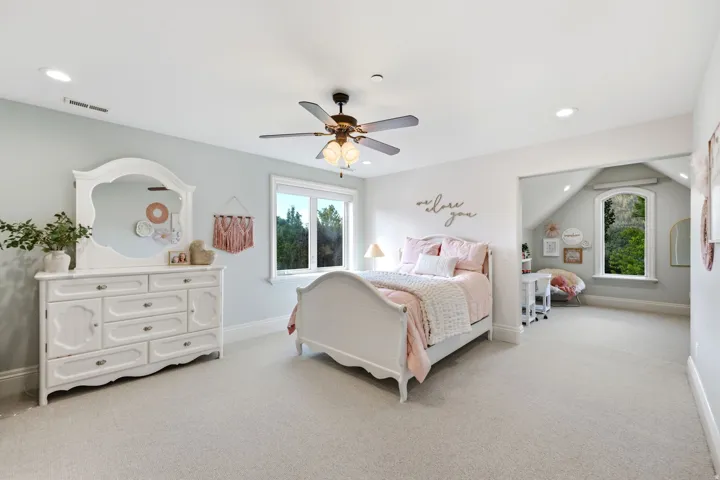 Recessed ceiling lighting, ceiling fan with integrated light, light-toned walls, and soft carpeting