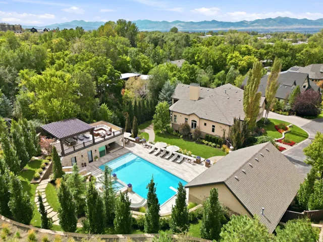 Expansive outdoor amenities featuring a large swimming pool, surrounding patio, and dedicated pool house with an upper-level covered terrace