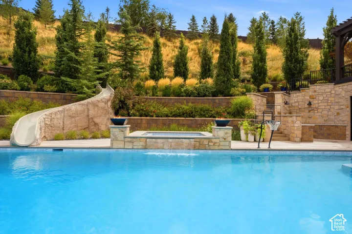 Resort-style pool with a rock-feature slide, integrated spa, and stone-clad retaining walls