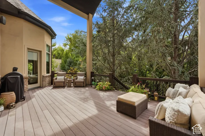 Expansive outdoor deck featuring composite decking, dark wood railings, and a stucco exterior with stone accents