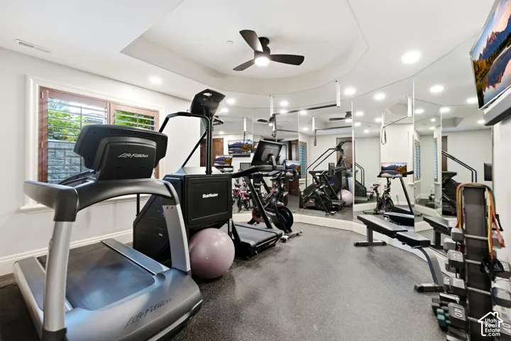 Recessed lighting, ceiling fan, mirrored wall, full-wall window, and tray ceiling