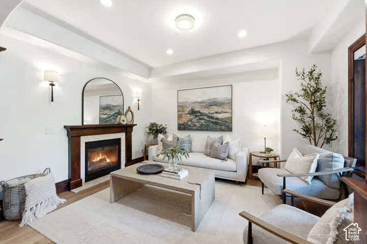 Recessed lighting, wood-finish flooring, fireplace with a wood mantle, decorative wall sconces, and a tray ceiling