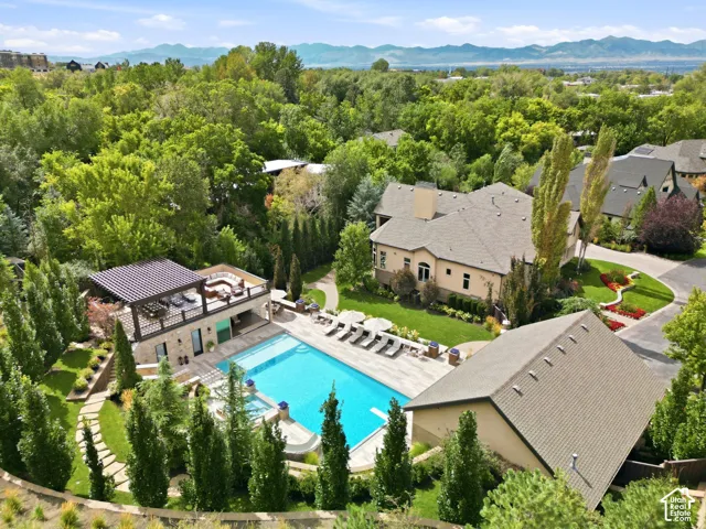 Expansive outdoor amenities featuring a large swimming pool, surrounding patio, and dedicated pool house with an upper-level covered terrace