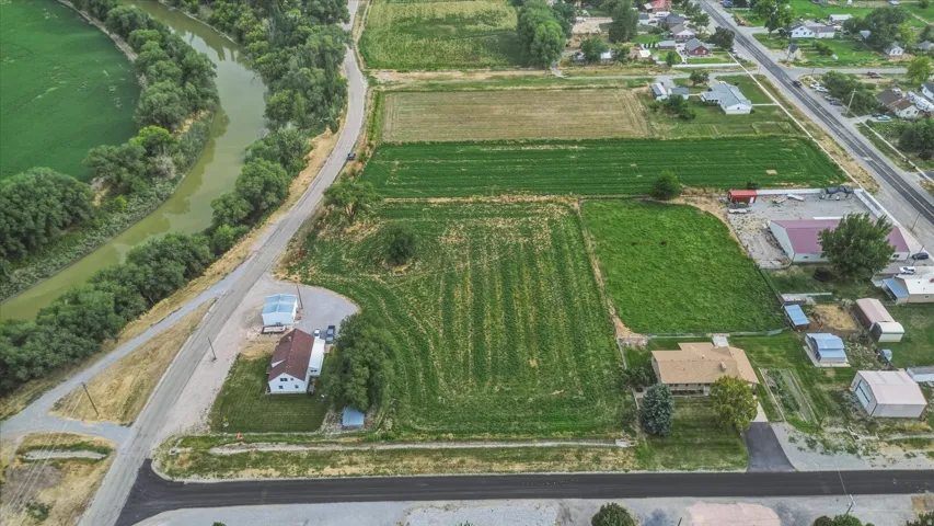 Property featuring a meandering river frontage, expansive green fields, established residential structures, and paved road access