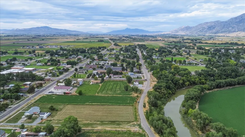 Lush green fields with surrounding mountains, a prominent river, and established residential areas