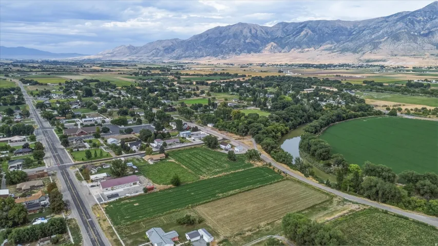 Expansive valley setting with agricultural fields, a winding river, and a mountain range backdrop