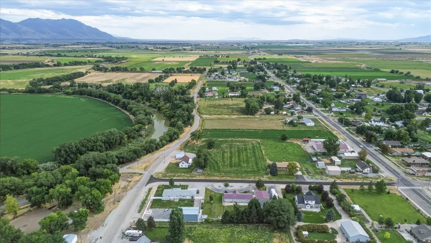 Aerial perspective showcasing expansive green fields, a river, and distant mountains